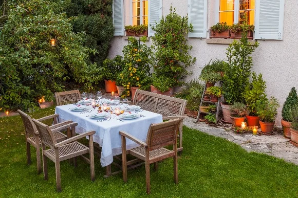 Gedeckter Tisch im Garten vor einem Haus.
